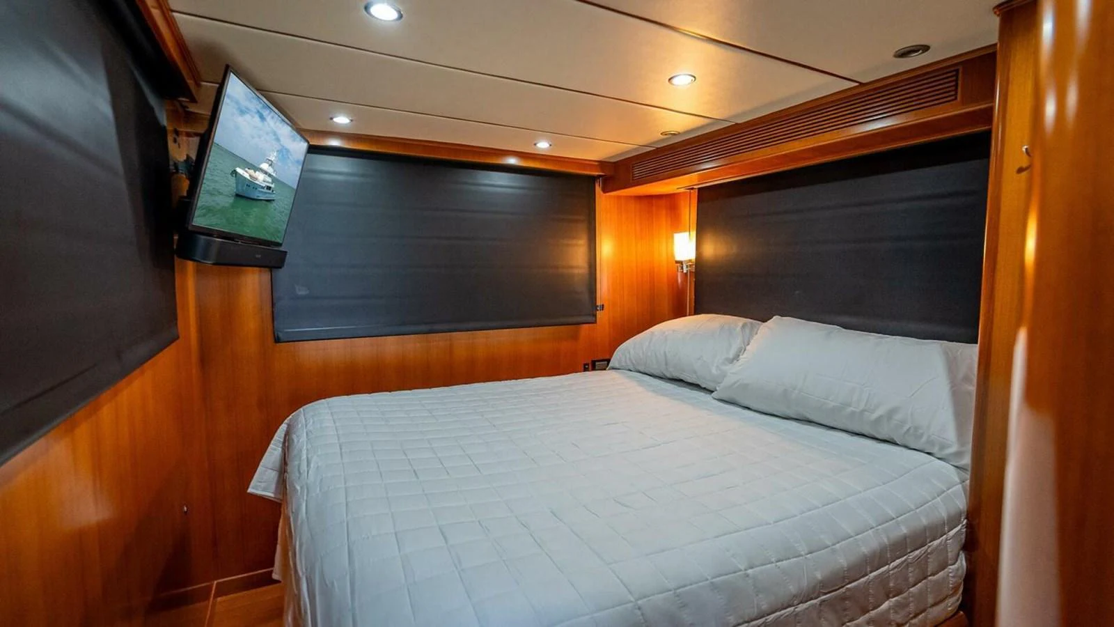 The cozy stateroom features a comfortable bed with elegant wood paneling and modern lighting. aboard TAKE 5 Yacht for Sale