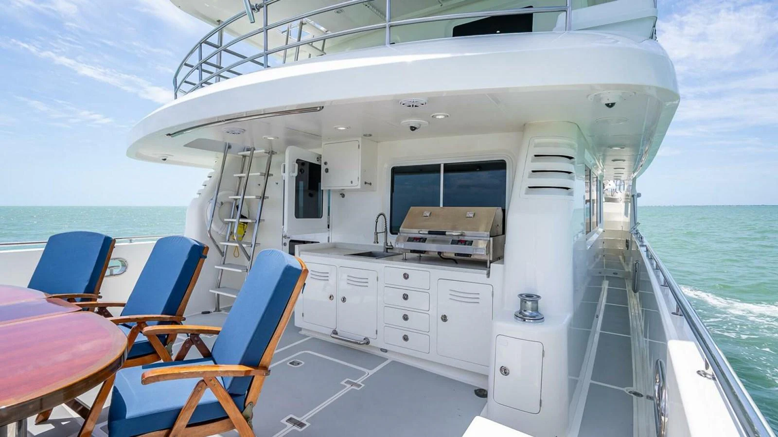 The aft deck features a dining area and a well-equipped outdoor kitchen with stunning sea views. aboard TAKE 5 Yacht for Sale