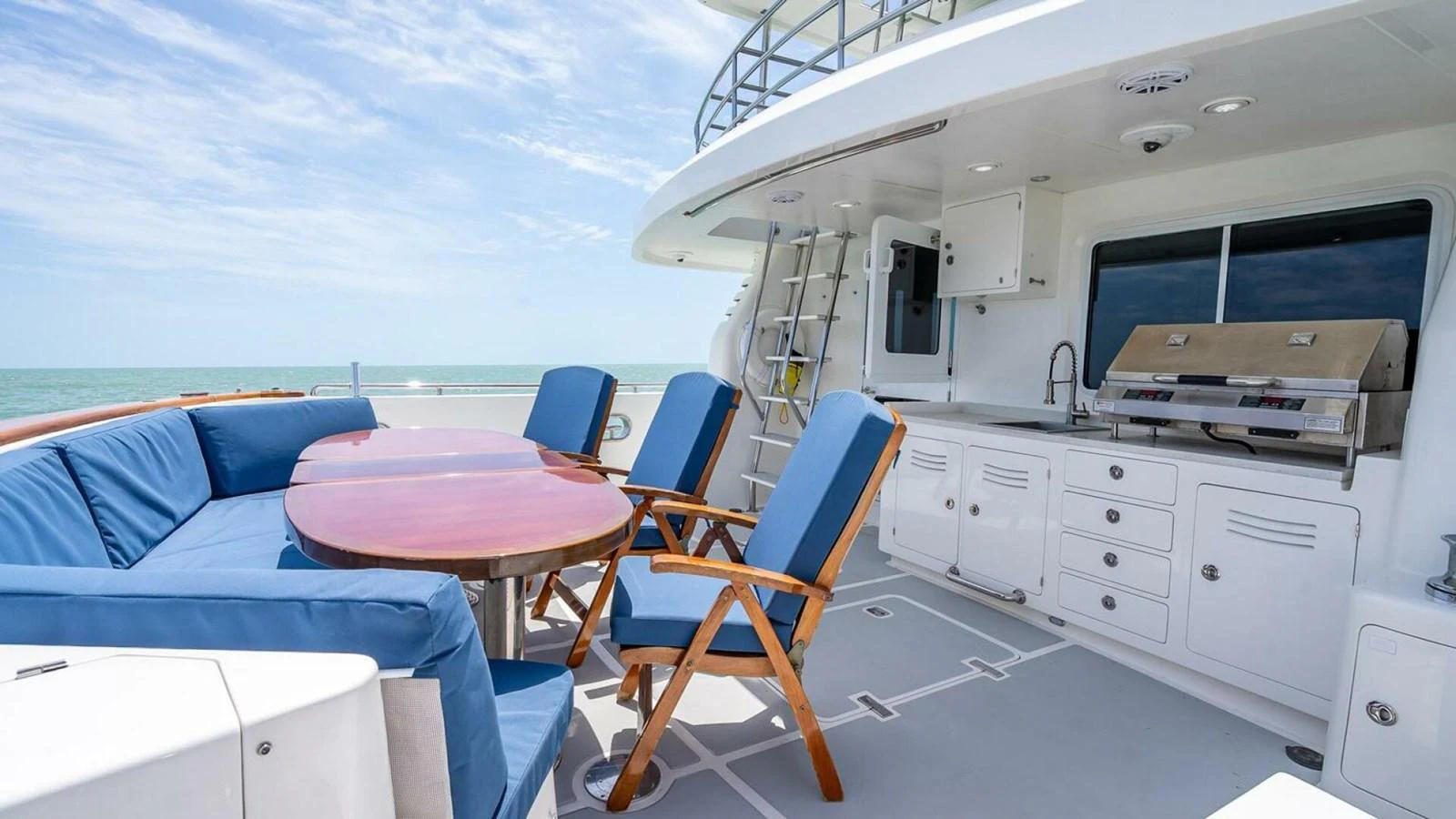 The aft deck features a comfortable seating area with a dining table and a built-in grill, perfect for outdoor dining and relaxation. aboard TAKE 5 Yacht for Sale