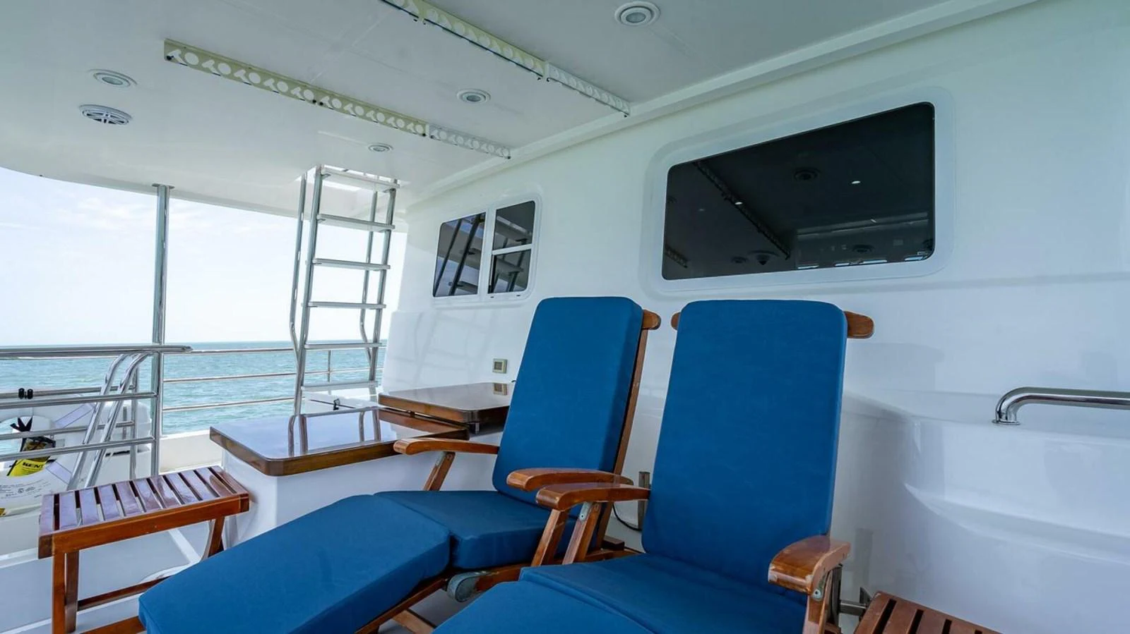 The aft deck features comfortable blue lounge chairs with a view of the ocean. aboard TAKE 5 Yacht for Sale