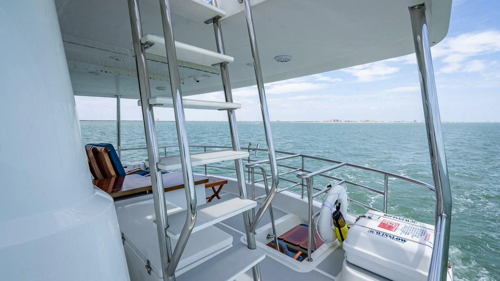 The aft deck offers a serene view of the open water, complemented by a sleek staircase leading to the upper deck. aboard TAKE 5 Yacht for Sale