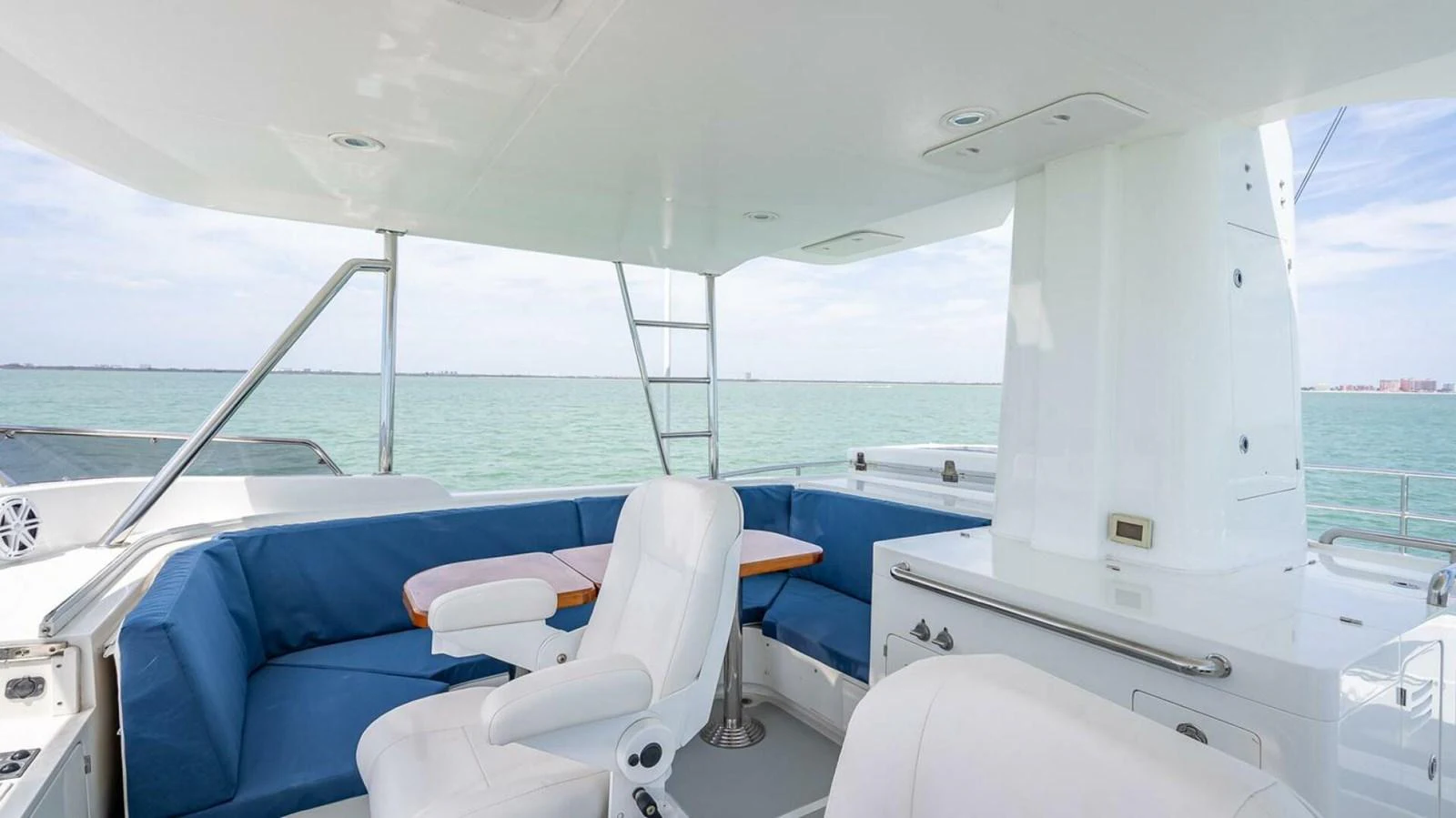 The flybridge offers a spacious seating area with comfortable white chairs and blue cushions, perfect for enjoying the view. aboard TAKE 5 Yacht for Sale