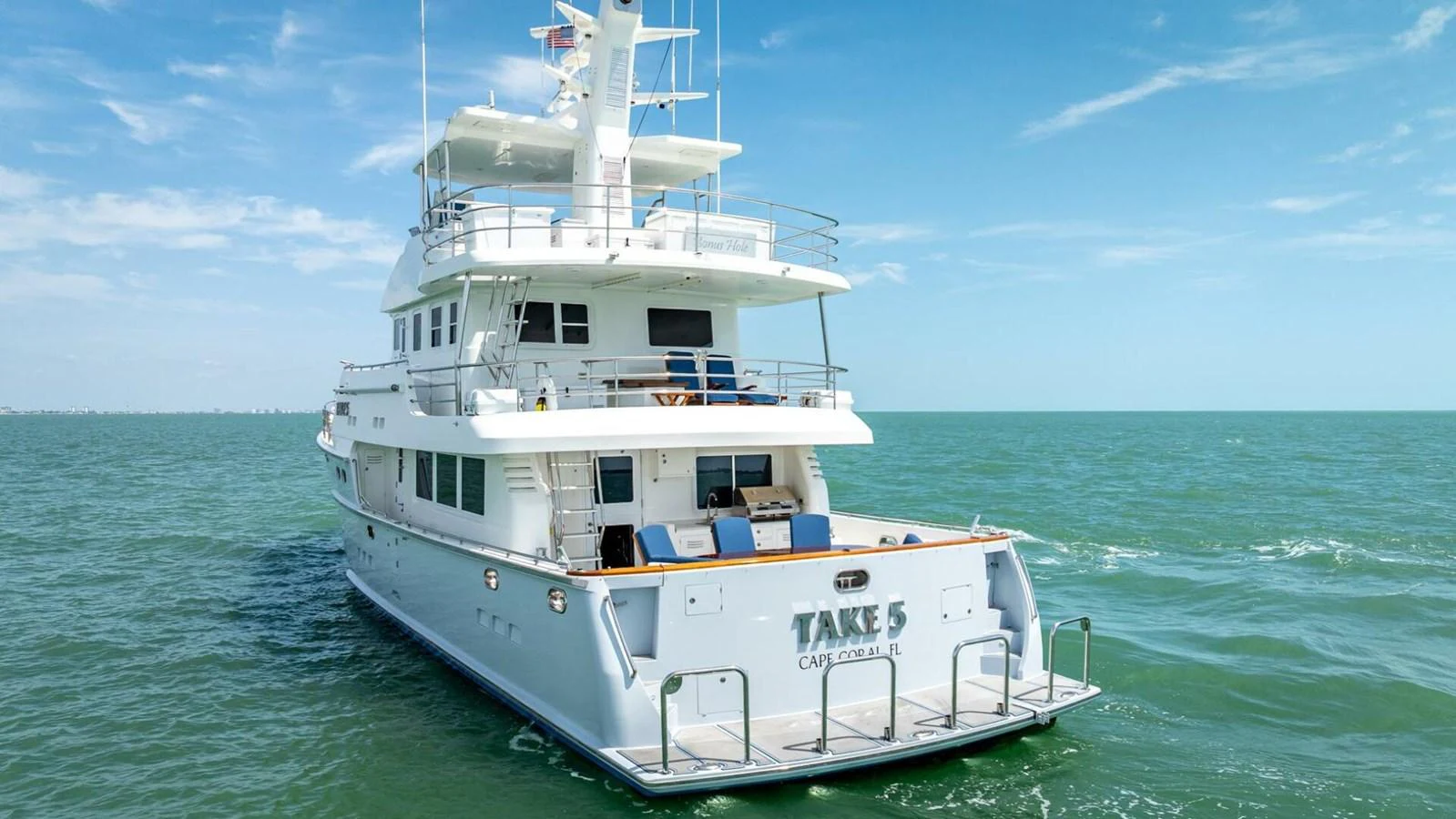 A luxurious yacht cruising on calm waters with a spacious aft deck. aboard TAKE 5 Yacht for Sale