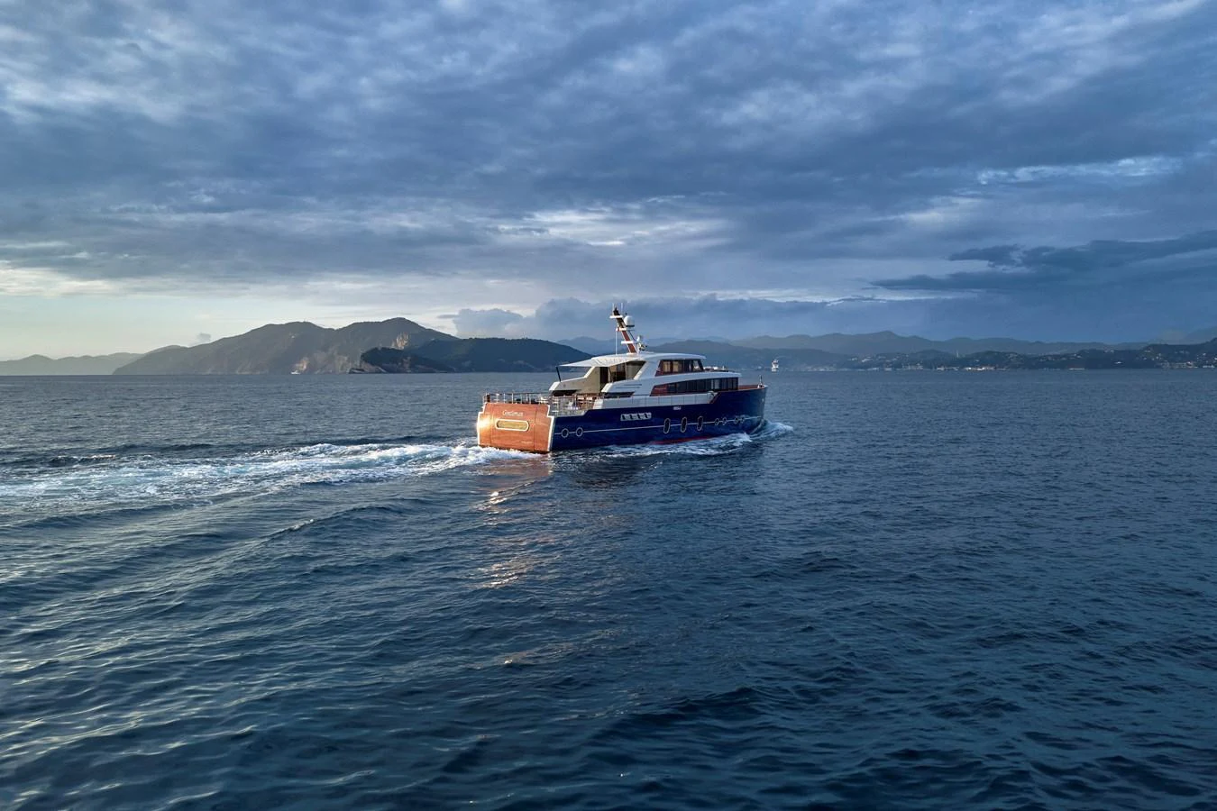 A sleek yacht cruises through calm waters against a backdrop of distant mountains. aboard PICCHIOTTI GENTLEMAN 24 Yacht for Sale