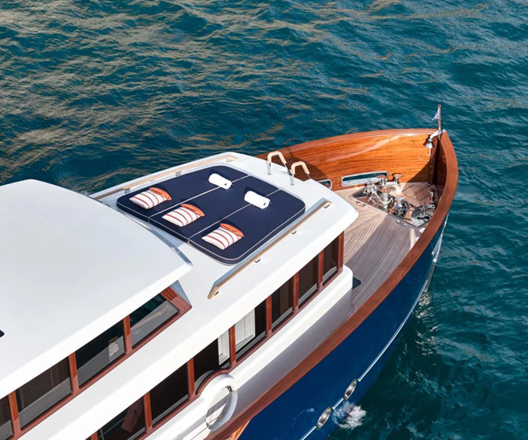 The yacht's foredeck features a sleek design with sun pads and a polished wooden finish, cruising gracefully on the water. aboard PICCHIOTTI GENTLEMAN 24 Yacht for Sale