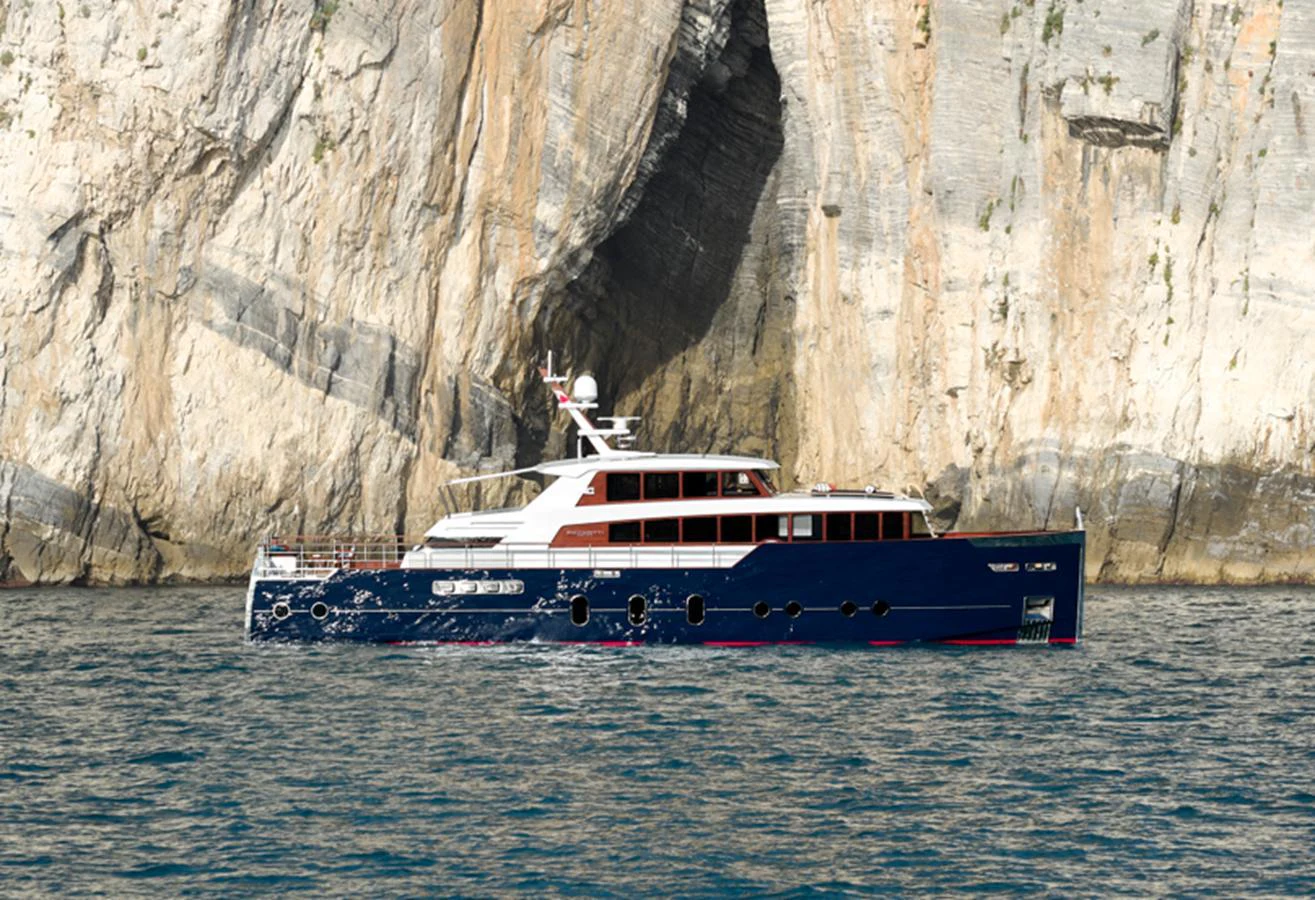 A stunning yacht cruises along a rocky coastline, showcasing its sleek design and elegant profile. aboard PICCHIOTTI GENTLEMAN 24 Yacht for Sale