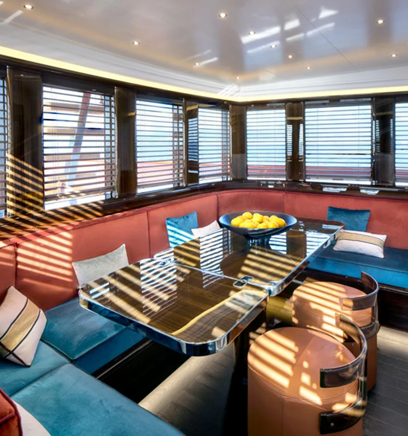 The yacht's dining area features a sleek table surrounded by comfortable seating, bathed in natural light through wooden blinds. aboard PICCHIOTTI GENTLEMAN 24 Yacht for Sale