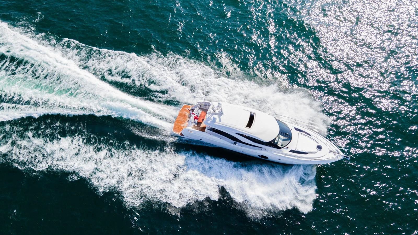 A sleek yacht cruises swiftly through the sparkling blue waters, leaving a trail of white wake behind. aboard NEPTUNUS 650E Yacht for Sale