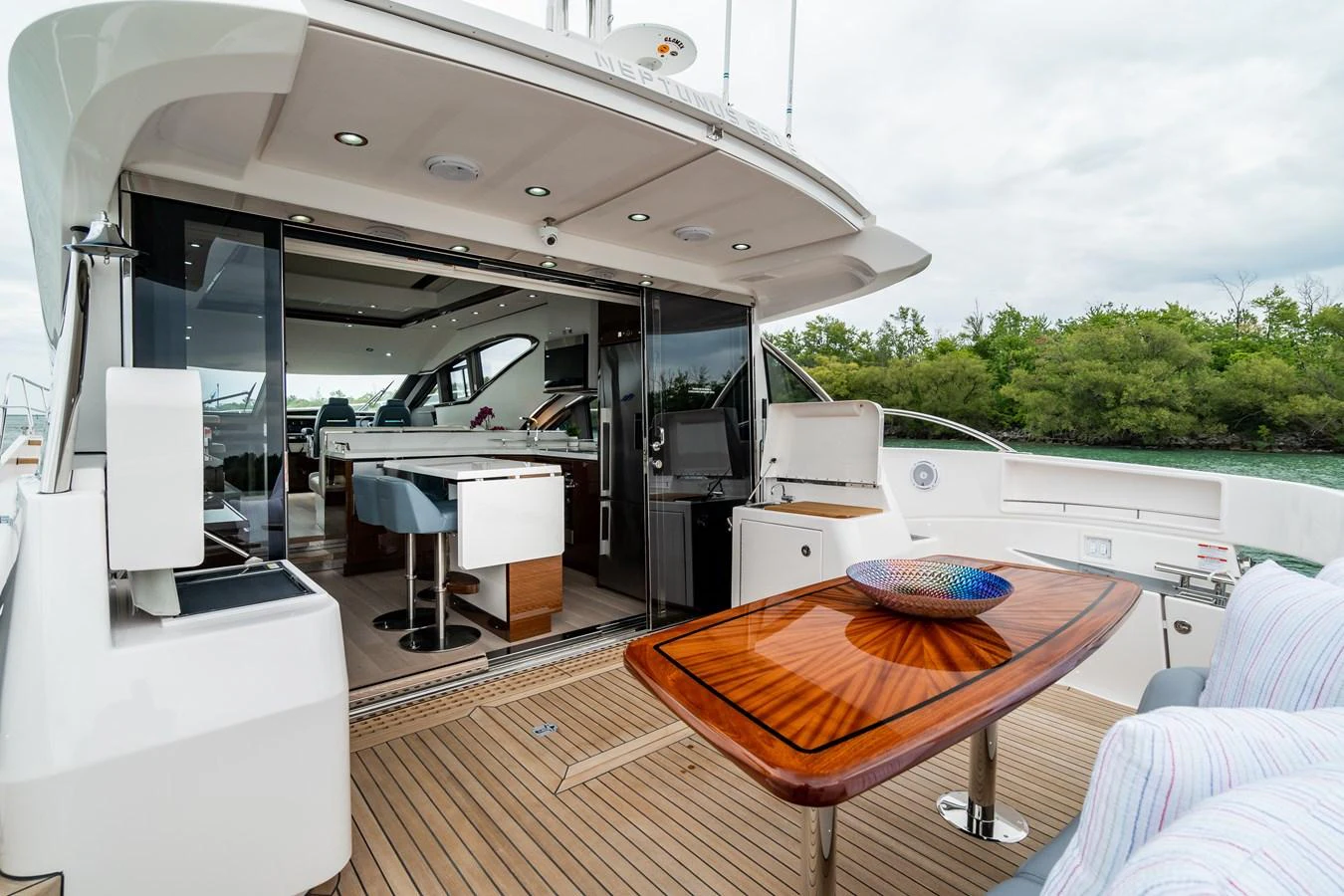 The aft deck offers a seamless transition between indoor and outdoor living spaces, featuring a stylish dining area and a view of the lush surroundings. aboard NEPTUNUS 650E Yacht for Sale