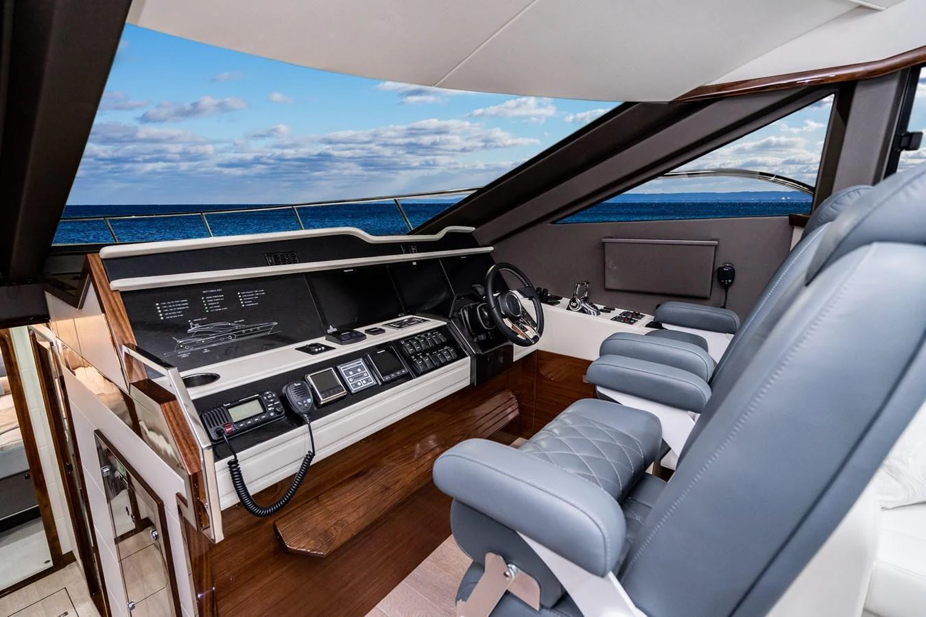 The helm station features luxurious seating and state-of-the-art navigation equipment with a stunning ocean view. aboard NEPTUNUS 650E Yacht for Sale