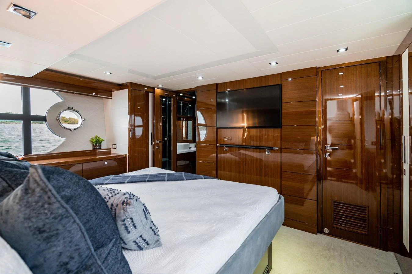 The stateroom features a luxurious bed, sleek wood paneling, and a large window with an ocean view. aboard NEPTUNUS 650E Yacht for Sale