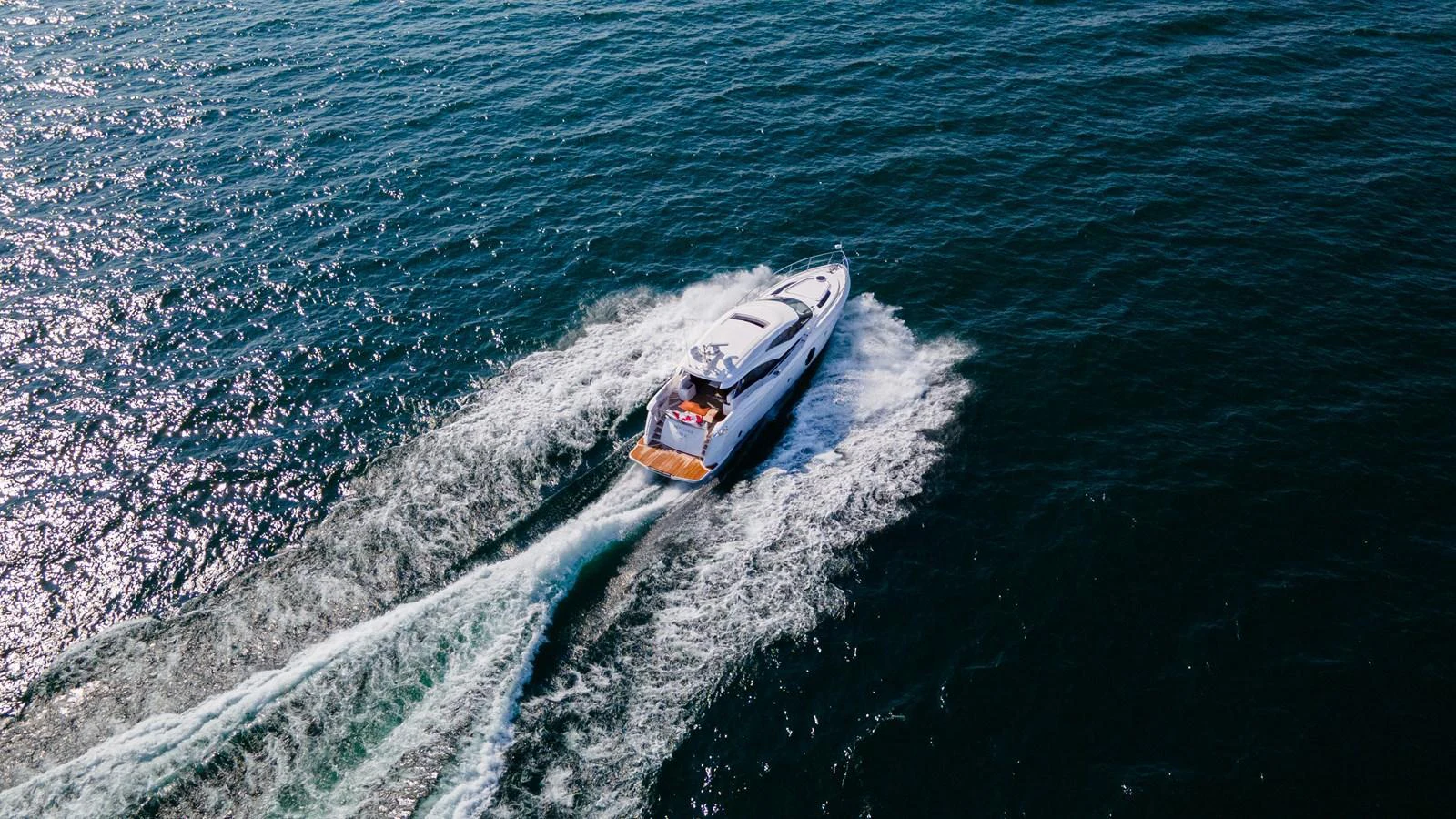 A sleek yacht cruises swiftly across the open water, leaving a trail of white wake behind. aboard NEPTUNUS 650E Yacht for Sale