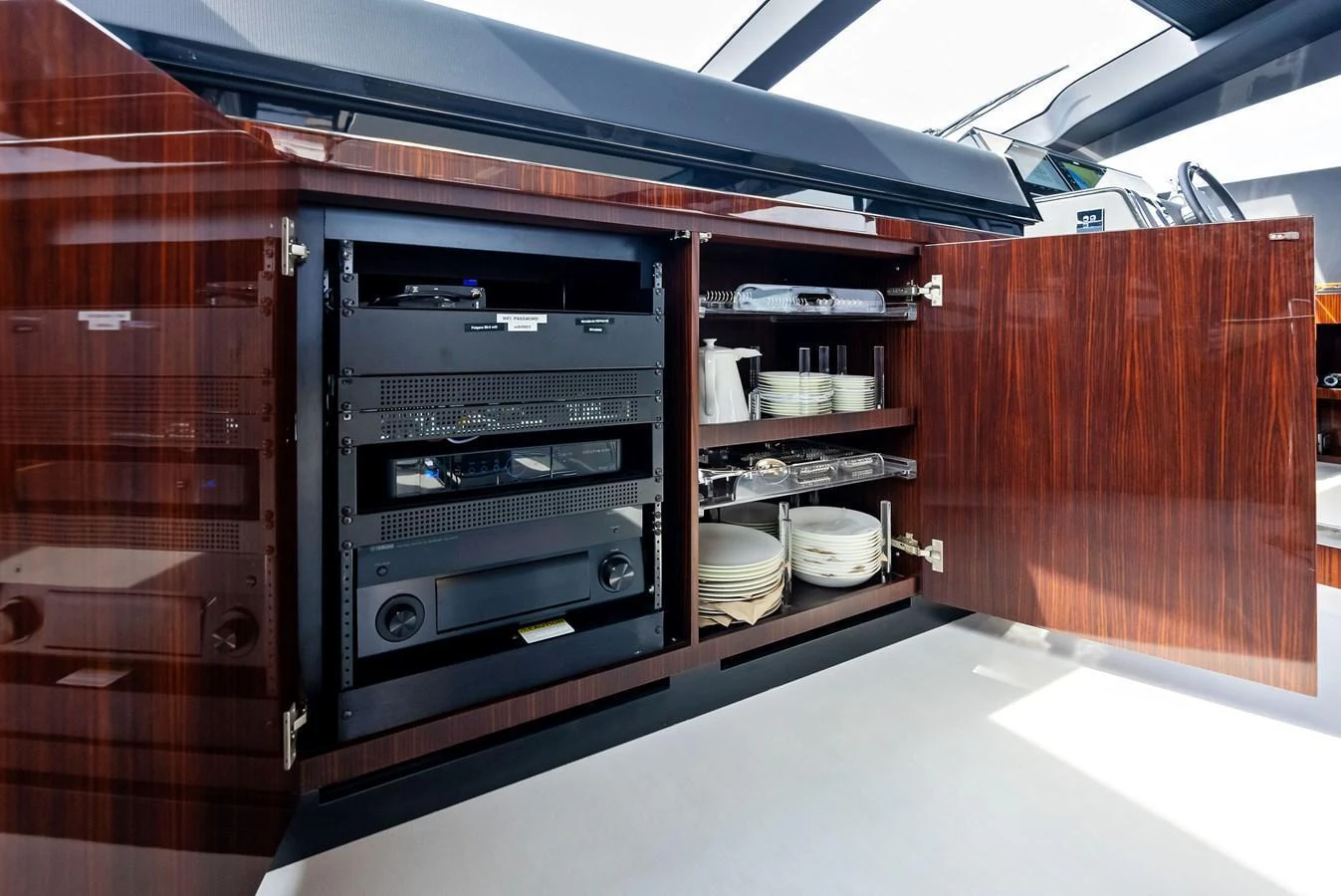 A detailed view of the yacht's storage cabinet showcasing electronic equipment and neatly organized dishware. aboard FERRETTI  TRADE Yacht for Sale