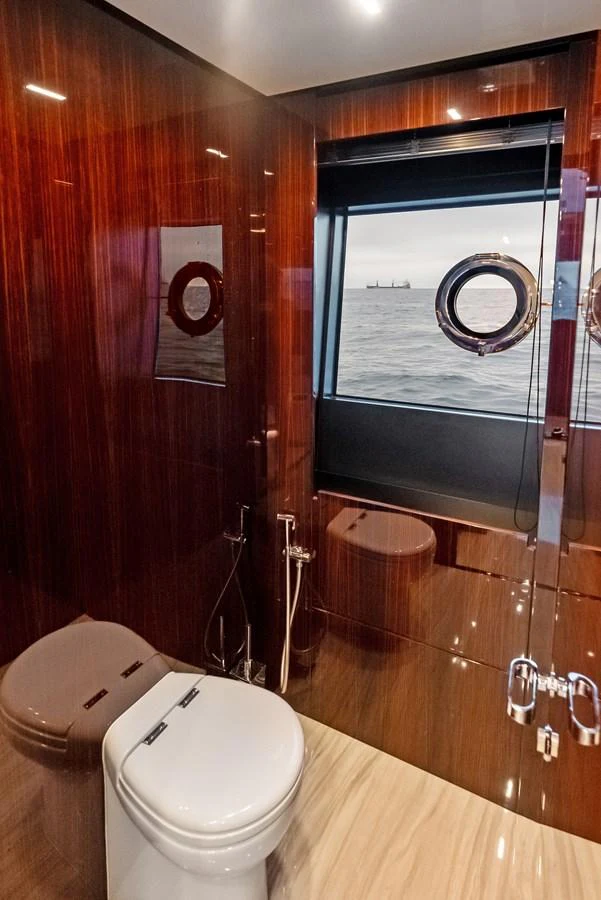 The yacht's head features a sleek design with rich wood paneling and a view of the sea through a porthole. aboard FERRETTI  TRADE Yacht for Sale
