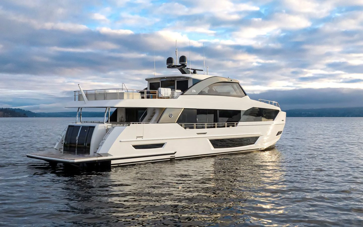 A sleek and modern yacht is anchored on calm waters under a partly cloudy sky. aboard STILL WATERS Yacht for Sale