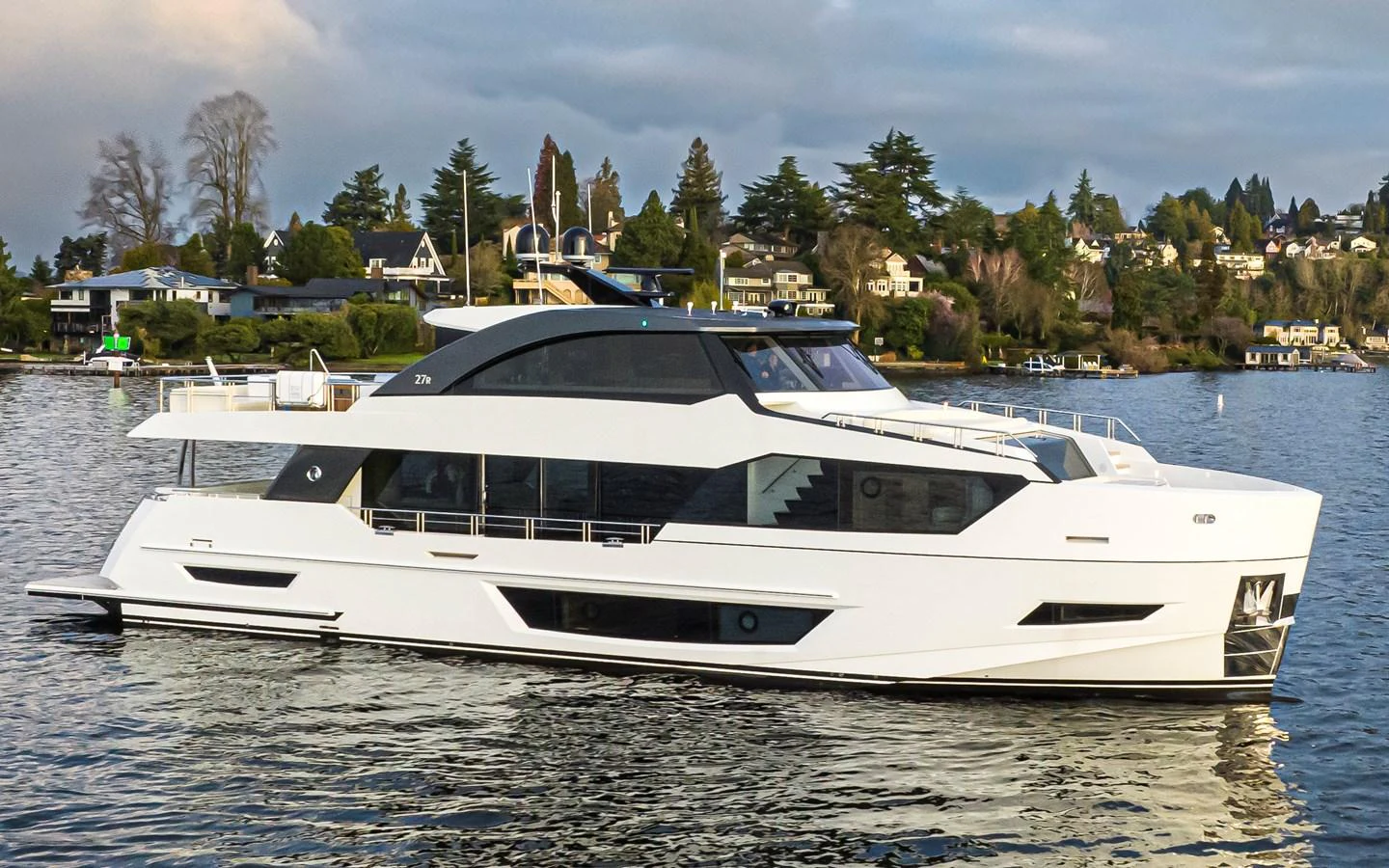 A sleek, modern yacht glides gracefully on calm waters with a scenic shoreline in the background. aboard STILL WATERS Yacht for Sale
