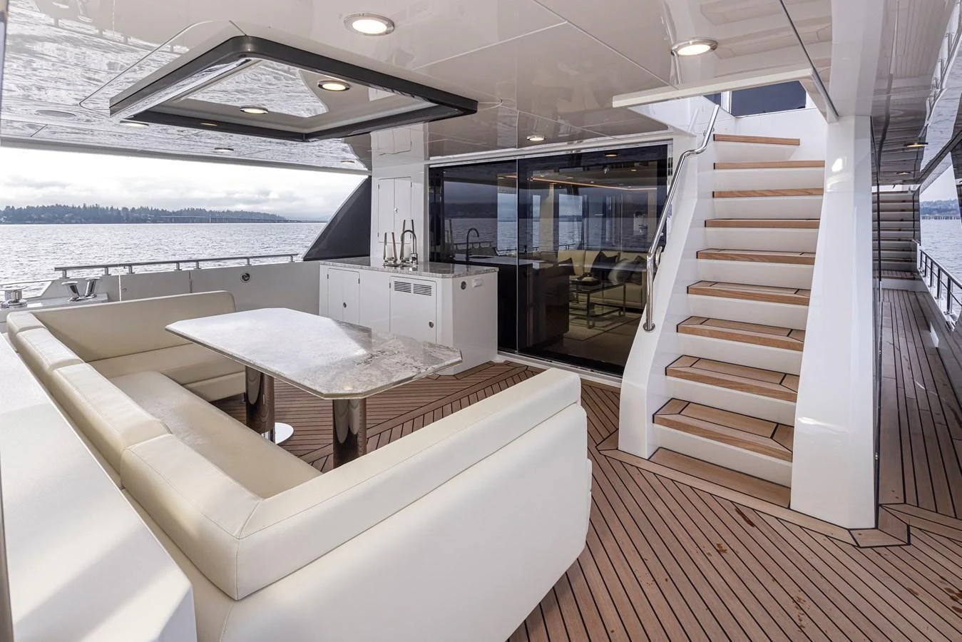 The aft deck features a spacious seating area with a table and stairs leading to the upper deck. aboard STILL WATERS Yacht for Sale