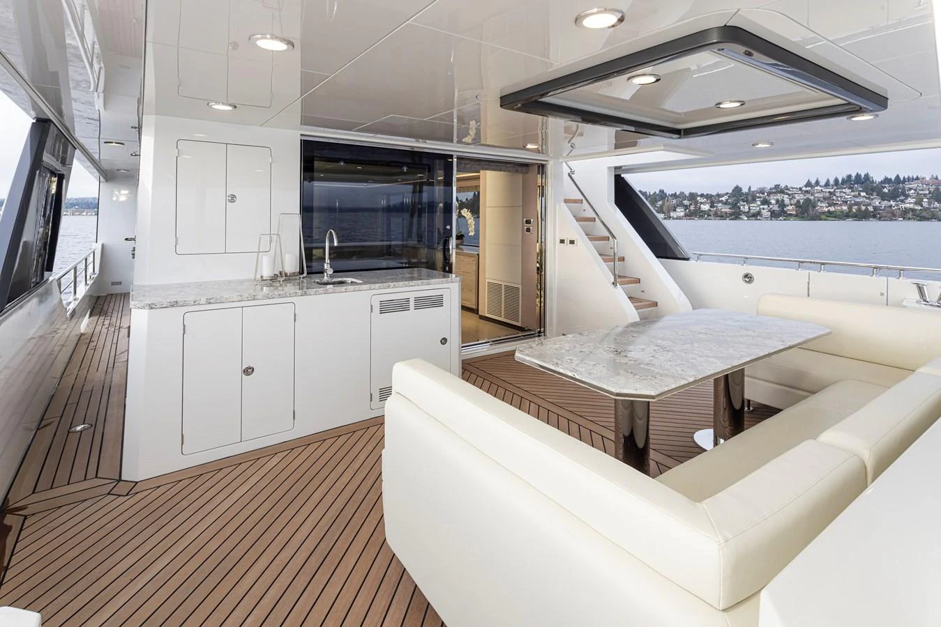 The aft deck features a luxurious seating area with a marble table and a well-equipped kitchenette. aboard STILL WATERS Yacht for Sale