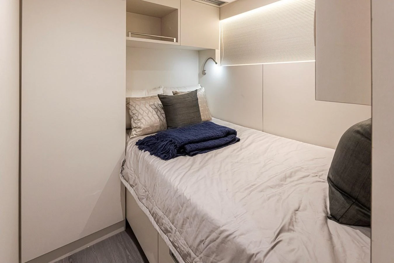A cozy stateroom featuring a neatly made bed with soft lighting and modern decor. aboard STILL WATERS Yacht for Sale