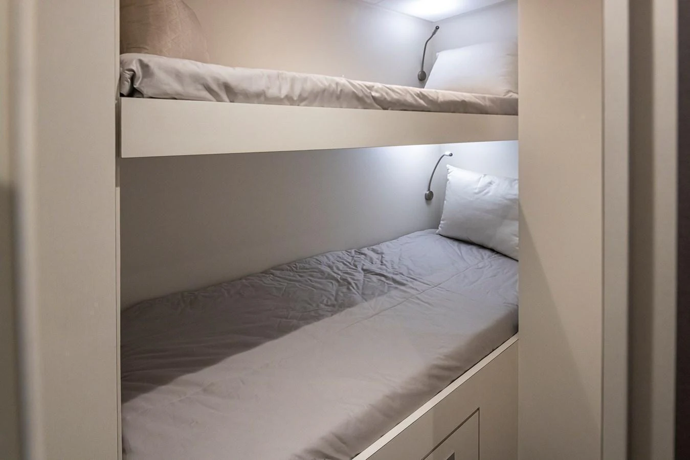 The image shows a cozy bunk cabin with two neatly made beds and soft lighting. aboard STILL WATERS Yacht for Sale