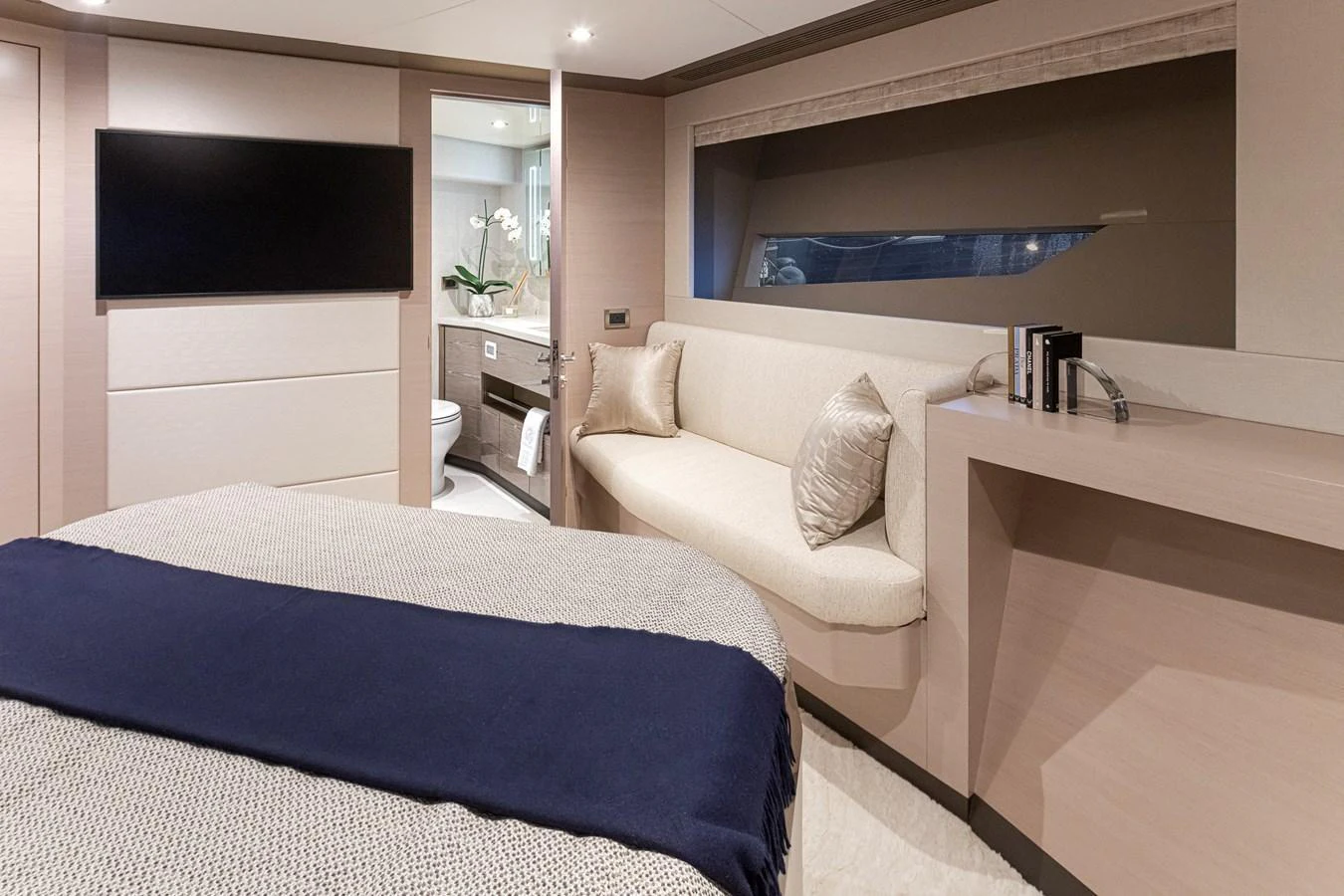 The stateroom features a cozy bed, a sleek TV, and a comfortable seating area with a view. aboard STILL WATERS Yacht for Sale