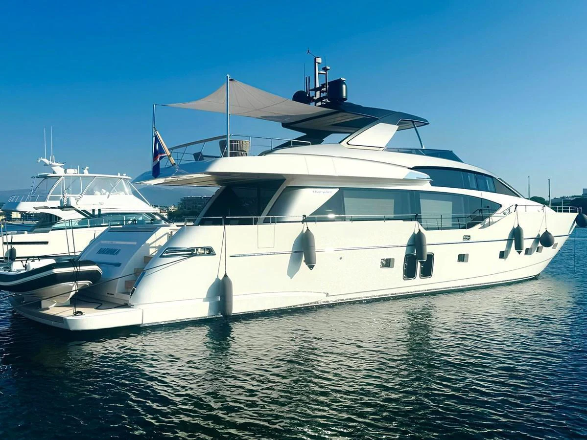 A sleek and modern yacht is docked in calm waters, showcasing its elegant design and spacious decks. aboard NADINKA Yacht for Sale