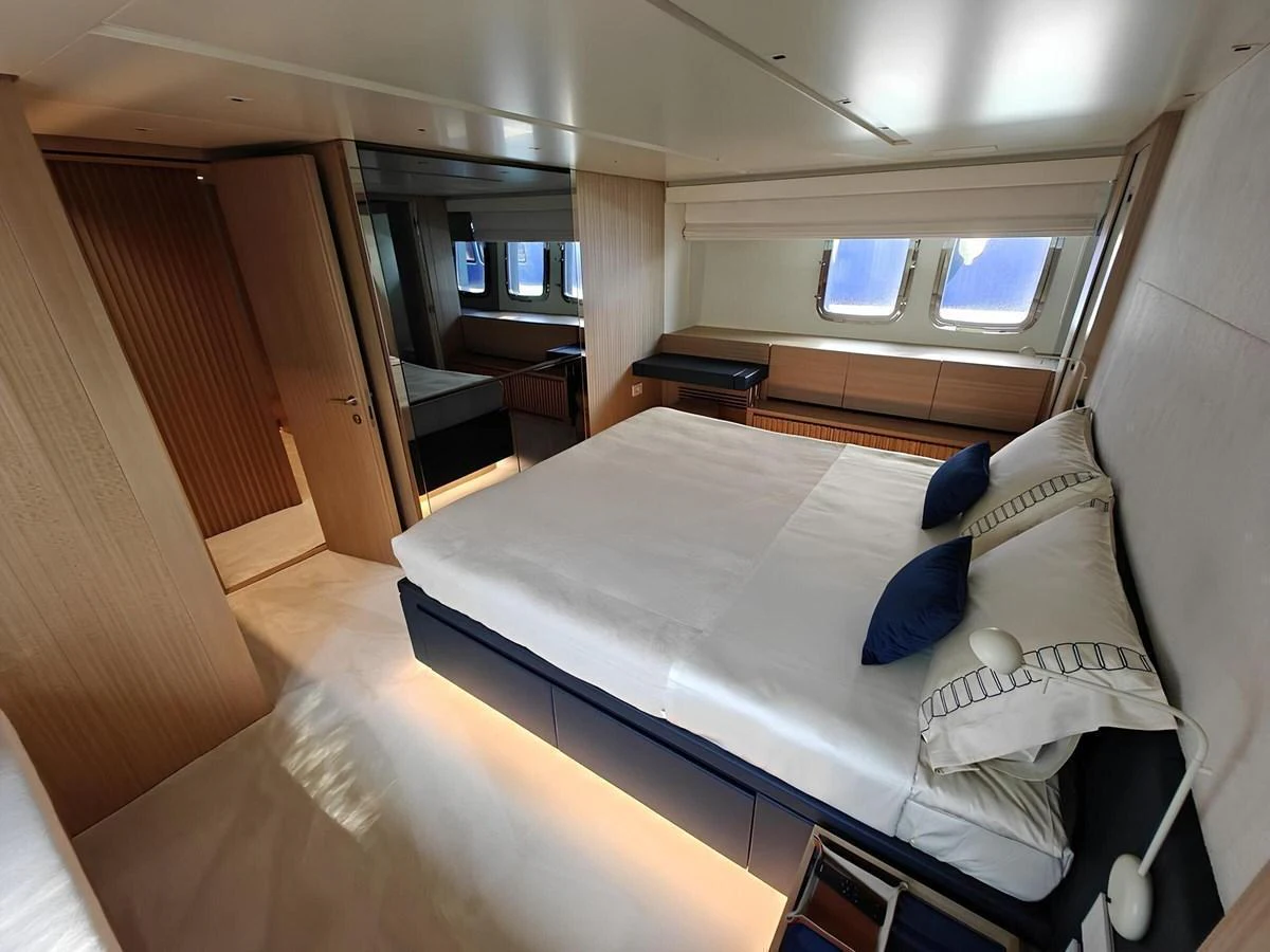The stateroom features a luxurious bed with elegant bedding and ample natural light from large windows. aboard NADINKA Yacht for Sale