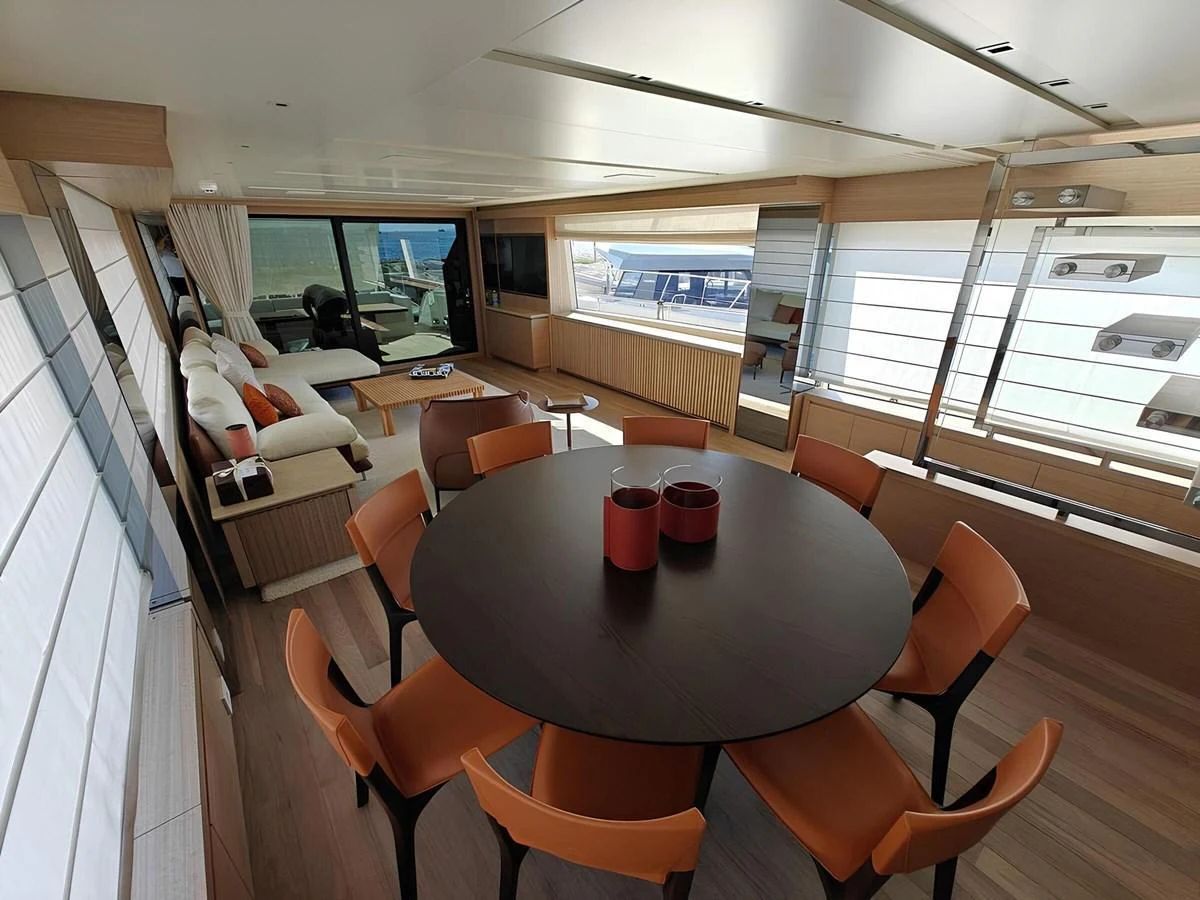 The yacht's salon features a spacious seating area with a round dining table and modern decor. aboard NADINKA Yacht for Sale