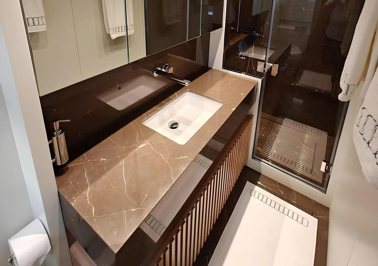 The yacht's bathroom features a sleek, modern design with a marble countertop and glass-enclosed shower. aboard NADINKA Yacht for Sale