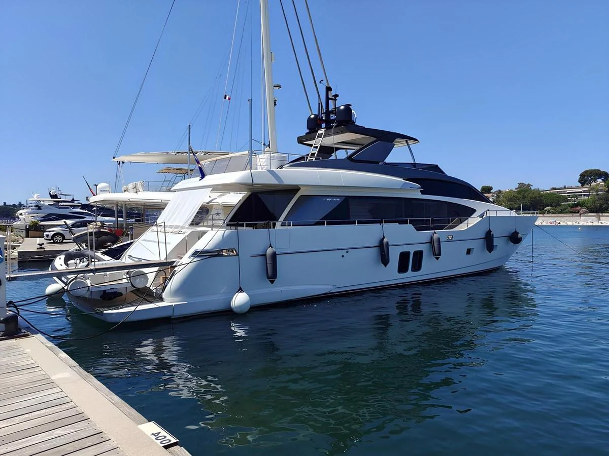 A sleek and modern yacht is docked at a marina, showcasing its elegant design and spacious deck. aboard NADINKA Yacht for Sale