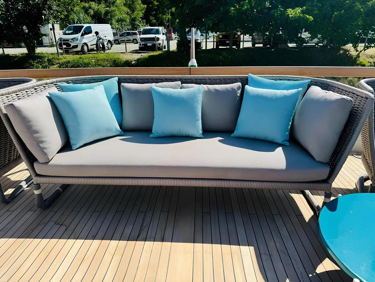 A stylish outdoor seating area on the yacht's deck, featuring a comfortable sofa with blue and gray cushions. aboard NADINKA Yacht for Sale