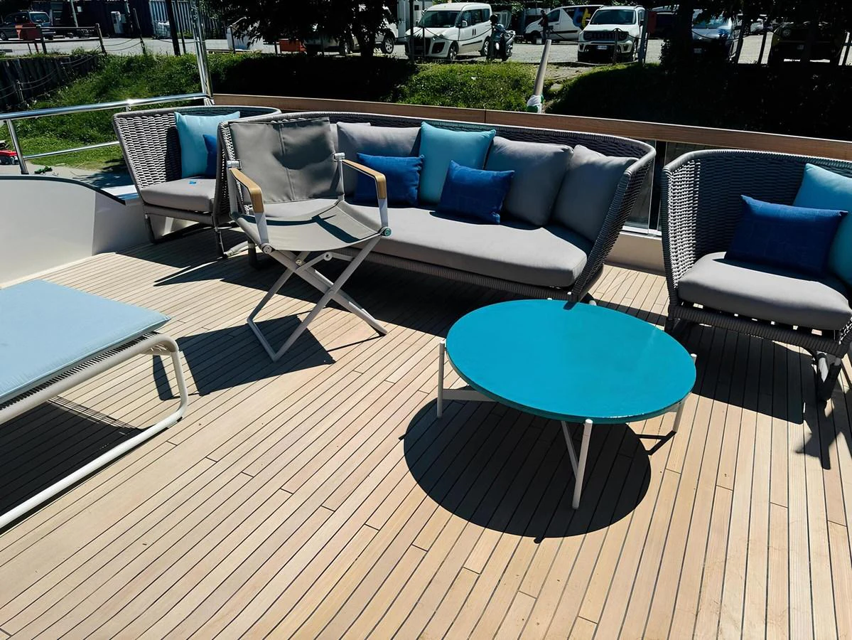 The sundeck features comfortable seating with stylish cushions and a vibrant blue table, perfect for relaxation. aboard NADINKA Yacht for Sale