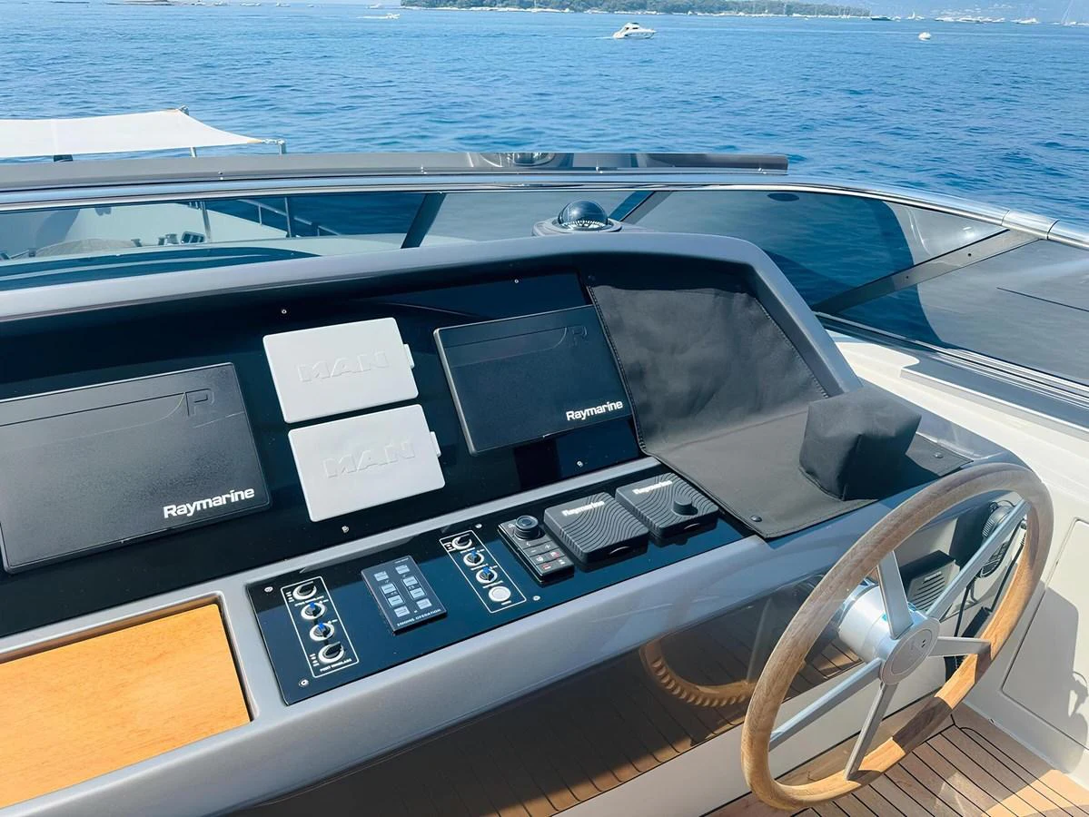 The helm station features advanced navigation equipment and a sleek steering wheel, set against a backdrop of serene waters. aboard NADINKA Yacht for Sale