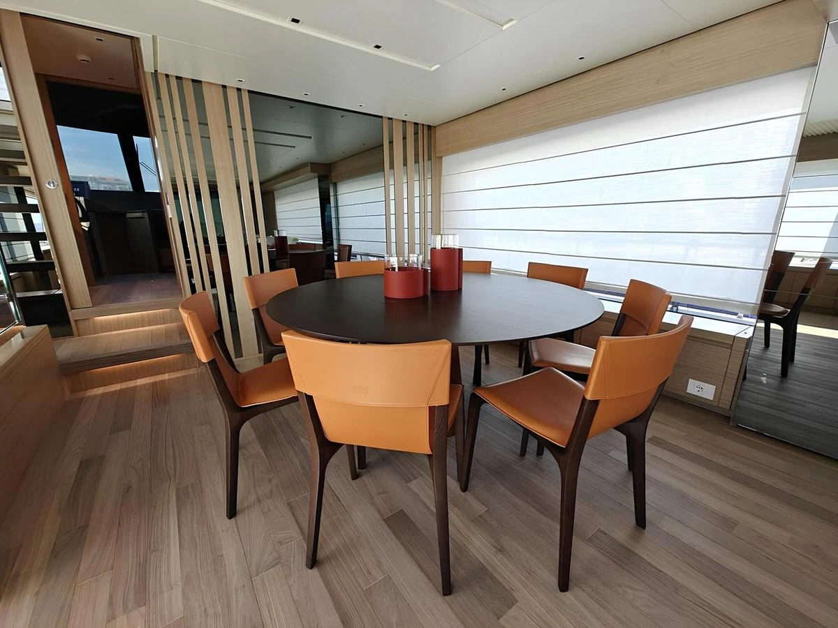 The yacht's dining area features a modern round table with stylish chairs, set in a bright and airy space. aboard NADINKA Yacht for Sale
