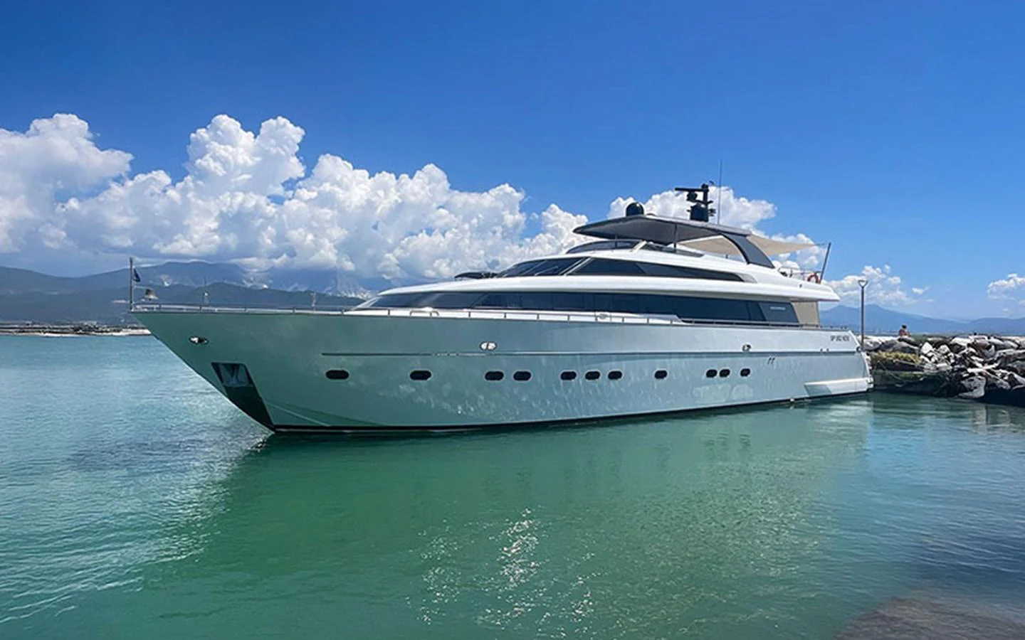 A sleek and modern yacht is docked in a serene harbor under a clear blue sky. aboard MEP TOGETHER Yacht for Sale