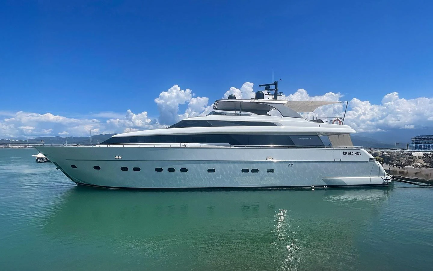 A sleek and modern yacht is docked in a serene marina under a clear blue sky. aboard MEP TOGETHER Yacht for Sale