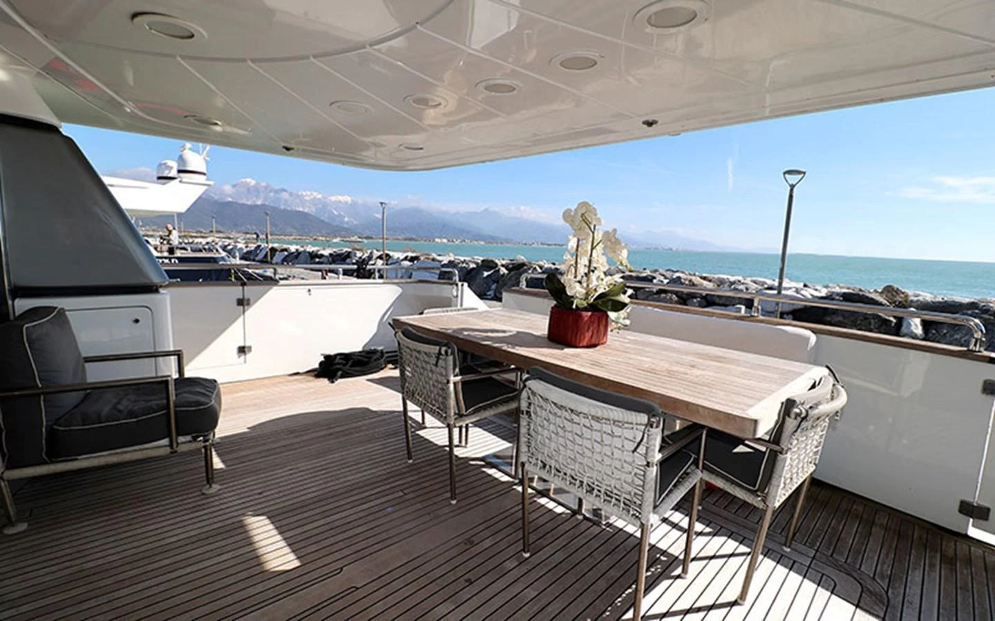 The aft deck features a stylish dining area with a wooden table and comfortable seating, perfect for enjoying meals with a view of the sea. aboard MEP TOGETHER Yacht for Sale
