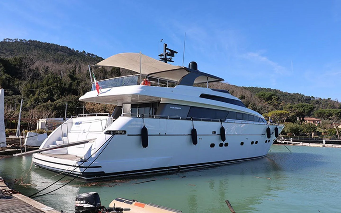 A sleek, modern yacht is docked in a serene marina with lush greenery in the background. aboard MEP TOGETHER Yacht for Sale