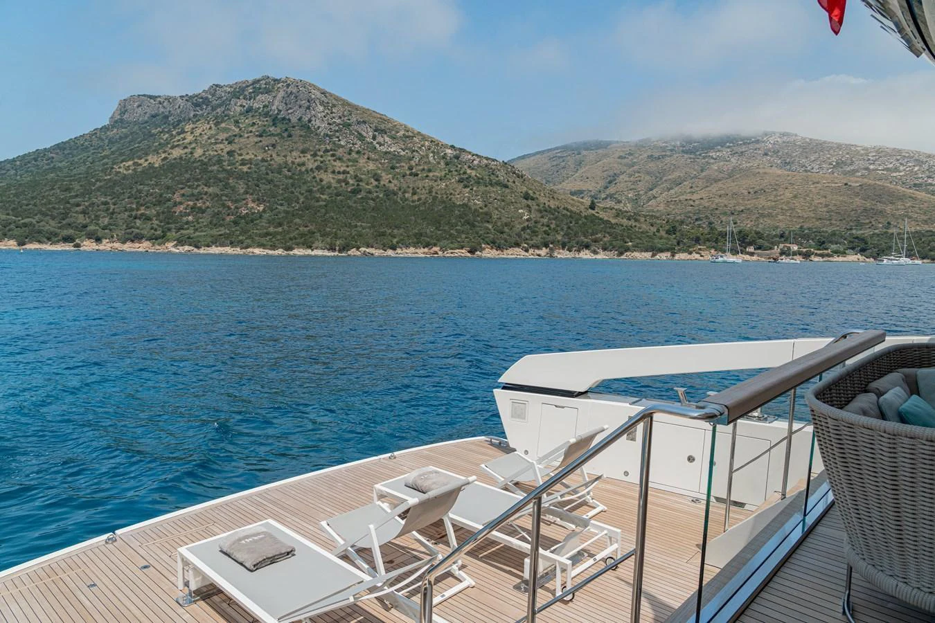 The aft deck offers a serene lounging area with sunbeds overlooking a stunning coastal landscape. aboard SANLORENZO SX 88 M&M Yacht for Sale