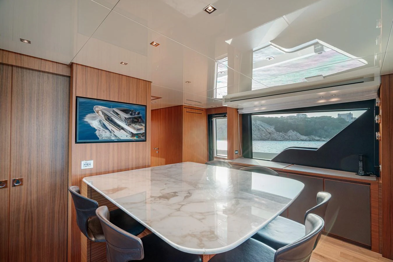 The yacht's dining area features a sleek marble table and modern seating, complemented by large windows offering scenic views. aboard SANLORENZO SX 88 M&M Yacht for Sale