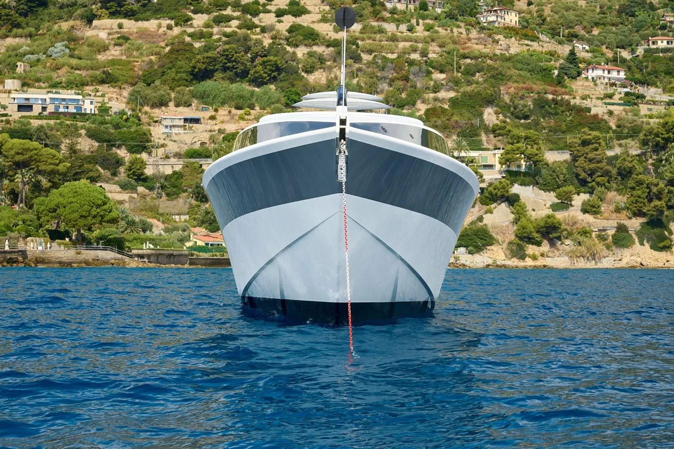 A sleek yacht is anchored in calm waters with a scenic coastal backdrop. aboard ZARKAVA Yacht for Sale