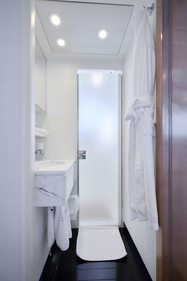 A sleek and modern yacht bathroom with a frosted glass door and elegant fixtures. aboard ZARKAVA Yacht for Sale