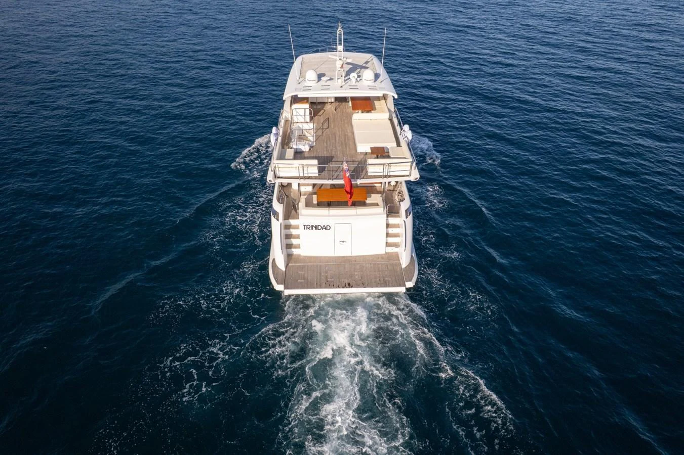 The yacht cruises smoothly over the water, showcasing its spacious aft deck and sleek design. aboard TRINIDAD Yacht for Sale