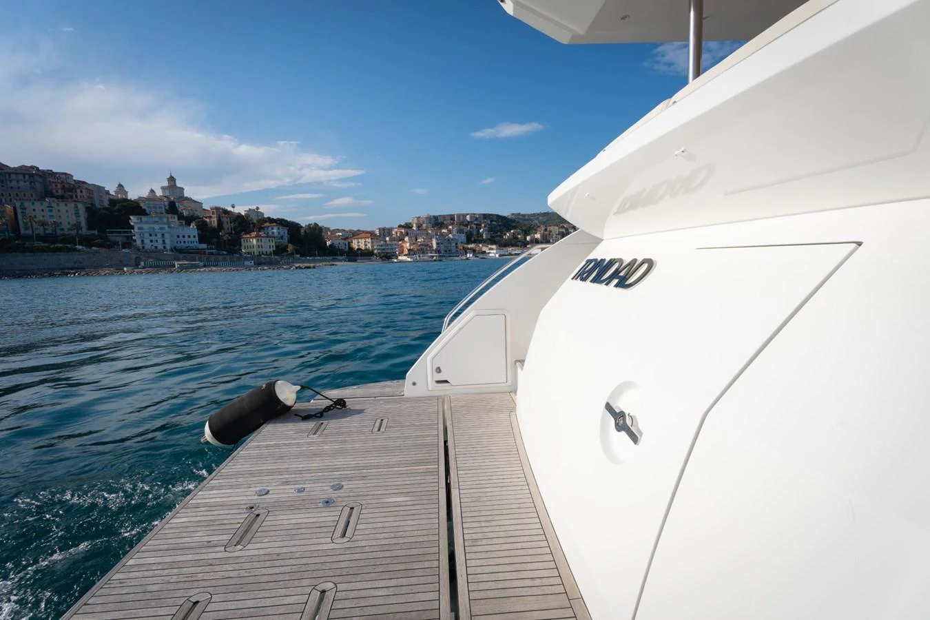The yacht is docked with a view of the surrounding coastal town. aboard TRINIDAD Yacht for Sale