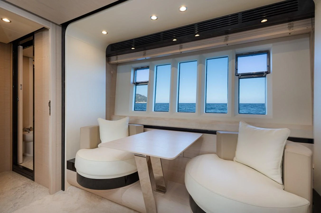 The yacht's interior features a cozy dining area with large windows offering a stunning ocean view. aboard TRINIDAD Yacht for Sale