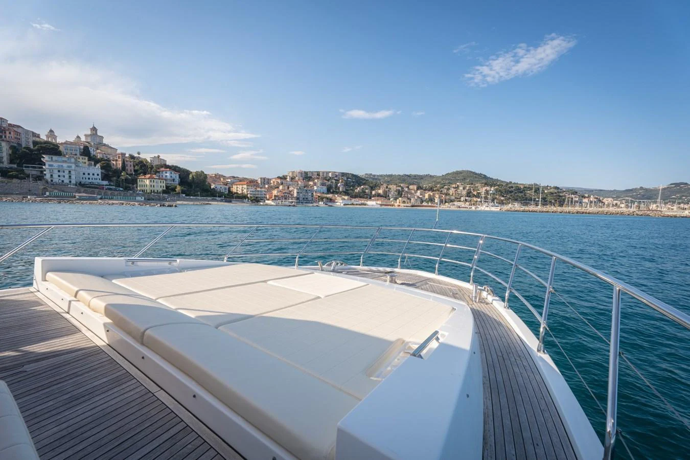 The yacht's foredeck features spacious sun pads with a stunning coastal backdrop. aboard TRINIDAD Yacht for Sale