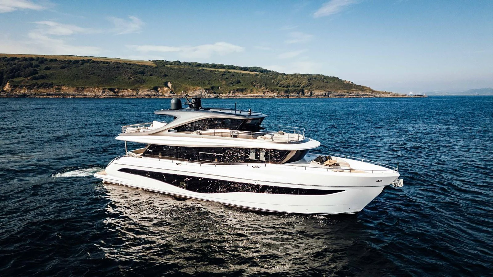 A sleek and modern yacht cruising on open waters with a scenic coastline in the background. aboard CHASE Yacht for Sale
