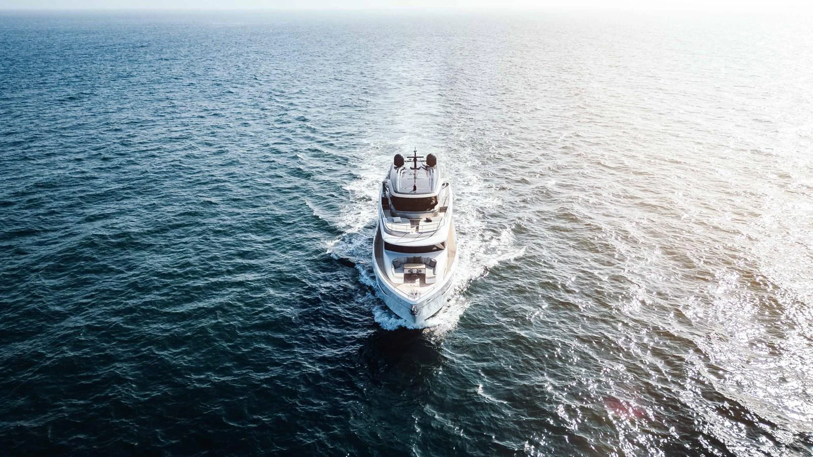 A sleek yacht cruises forward on the open sea, creating a serene wake behind it. aboard CHASE Yacht for Sale