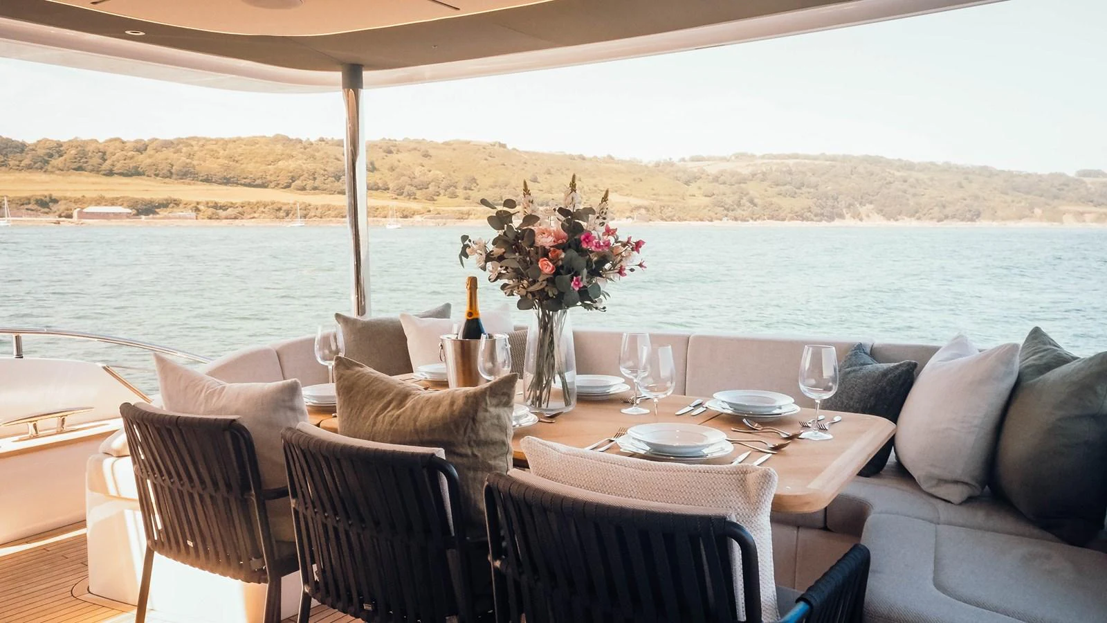 The aft deck features an elegant dining area with a picturesque view of the water and surrounding landscape. aboard CHASE Yacht for Sale