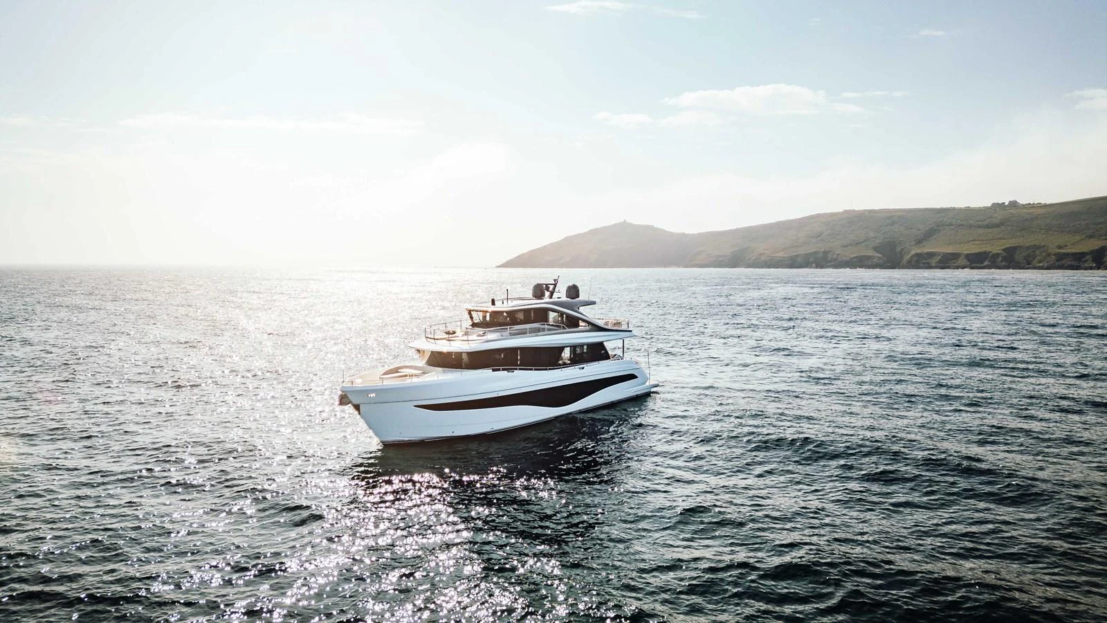 A sleek and modern yacht cruising on open waters with a scenic coastline in the background. aboard CHASE Yacht for Sale